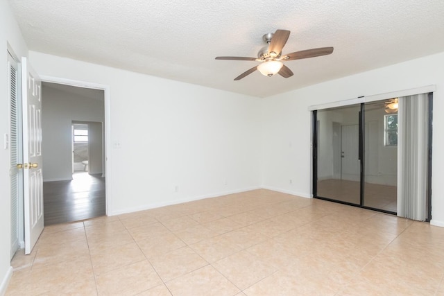 unfurnished room with a textured ceiling, ceiling fan, and light tile patterned flooring