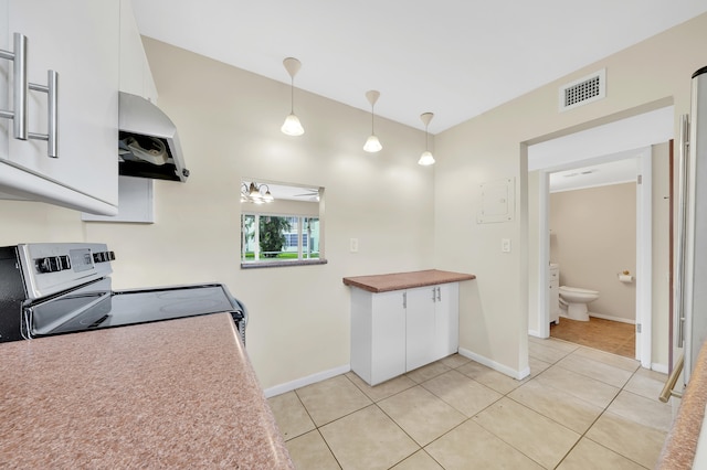 kitchen featuring ceiling fan, hanging light fixtures, light tile patterned floors, electric stove, and white cabinets