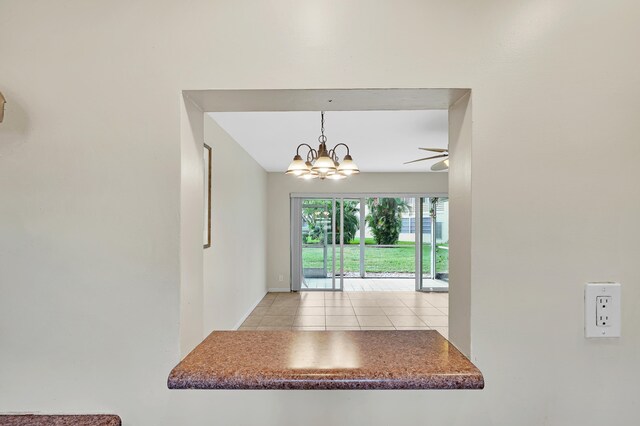 unfurnished dining area with light tile patterned floors and ceiling fan with notable chandelier