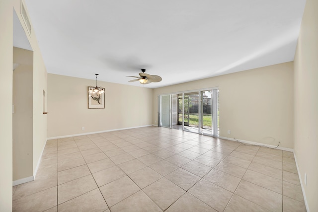 tiled spare room featuring ceiling fan with notable chandelier