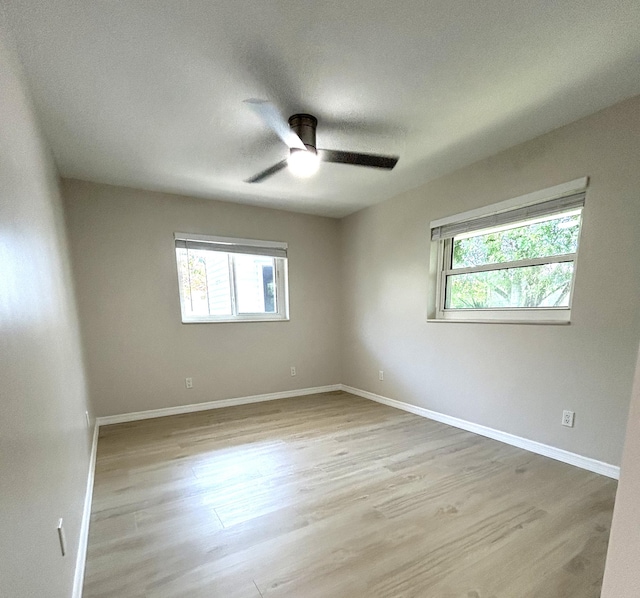 empty room with baseboards, ceiling fan, and light wood finished floors