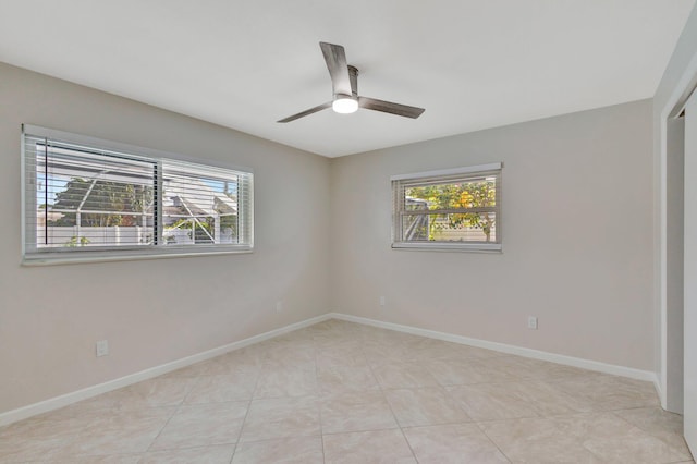 spare room with light tile patterned floors, ceiling fan, baseboards, and a wealth of natural light