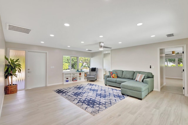 living area with light wood-style flooring, a healthy amount of sunlight, and visible vents