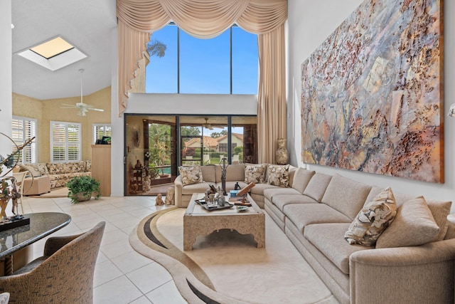 tiled living room with ceiling fan, a skylight, and high vaulted ceiling