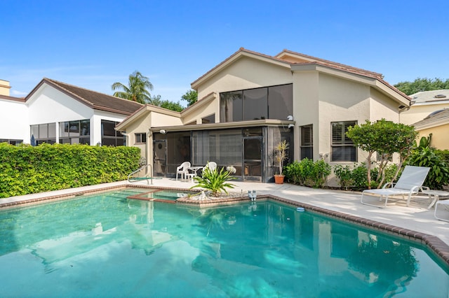 rear view of property with a fenced in pool, a sunroom, and a patio