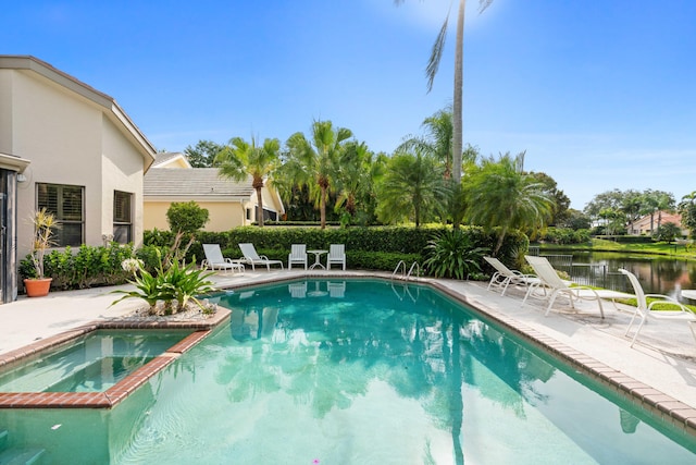 view of swimming pool with an in ground hot tub, a water view, and a patio