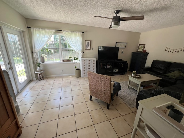 living room with ceiling fan, light tile patterned floors, and a textured ceiling