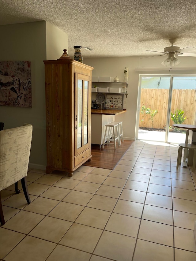 dining area with ceiling fan, light tile patterned flooring, and a textured ceiling