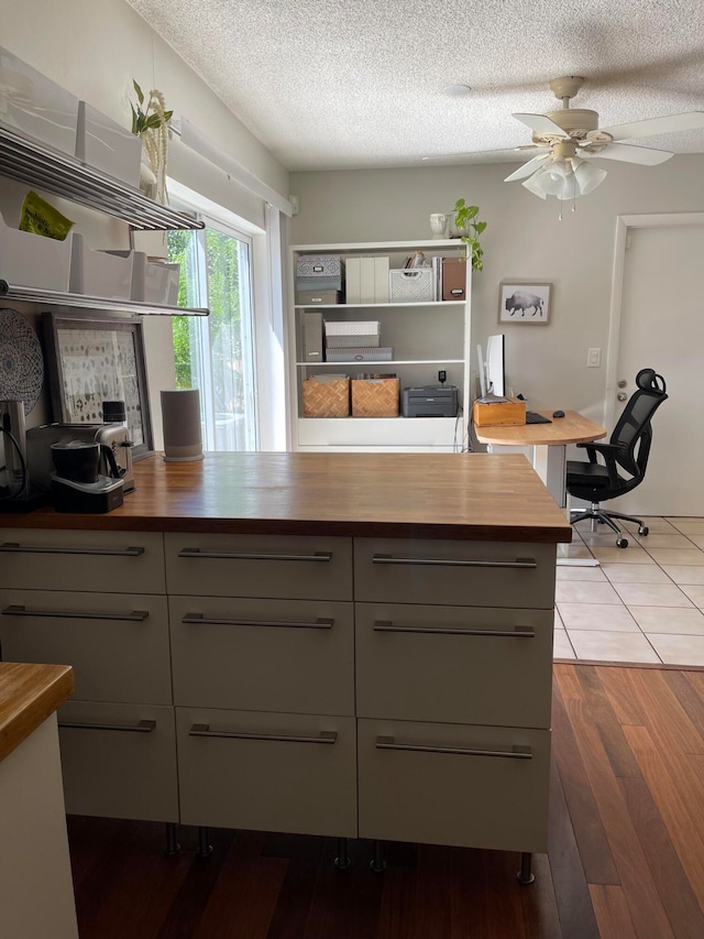 kitchen featuring dark hardwood / wood-style floors, gray cabinets, ceiling fan, a textured ceiling, and butcher block counters