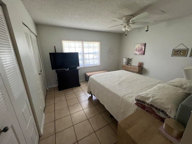 bedroom with ceiling fan, a closet, light tile patterned flooring, and a textured ceiling