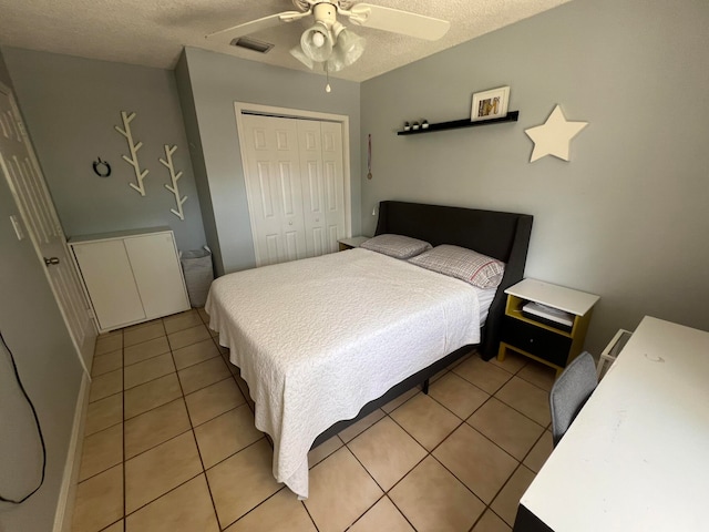 bedroom featuring ceiling fan, light tile patterned floors, a textured ceiling, and a closet