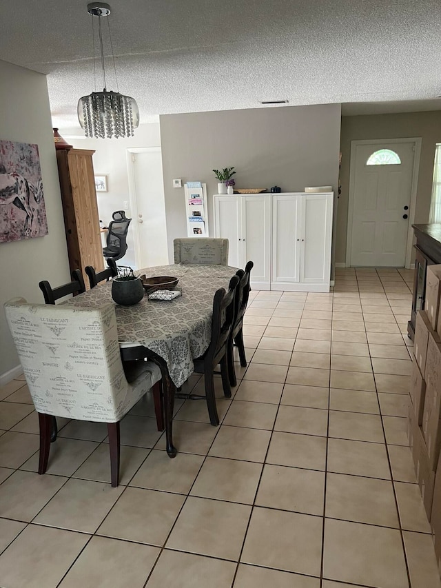 tiled dining area with a textured ceiling and an inviting chandelier