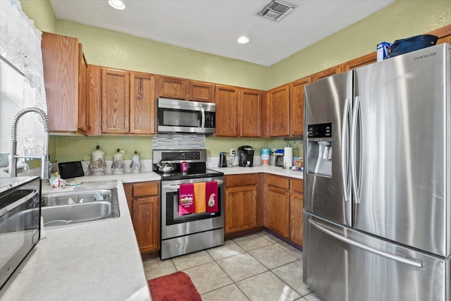 kitchen featuring light tile patterned floors, stainless steel appliances, and sink