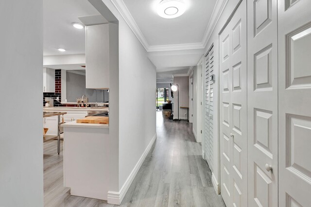 washroom with light wood-type flooring, crown molding, and washing machine and clothes dryer