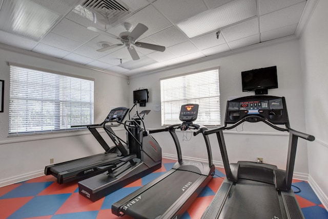 exercise room with a paneled ceiling, ceiling fan, and crown molding