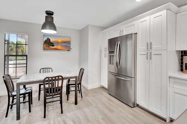 kitchen with white cabinets, stainless steel fridge, tasteful backsplash, and light hardwood / wood-style flooring