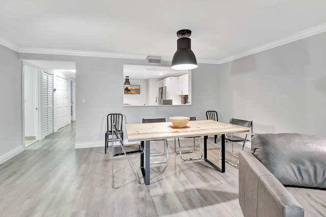 dining room with ornamental molding and light hardwood / wood-style flooring