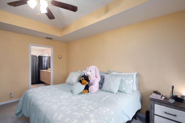 bedroom featuring ensuite bathroom, carpet, ceiling fan, and a tray ceiling