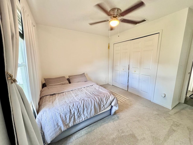 bedroom featuring light colored carpet, a closet, and ceiling fan