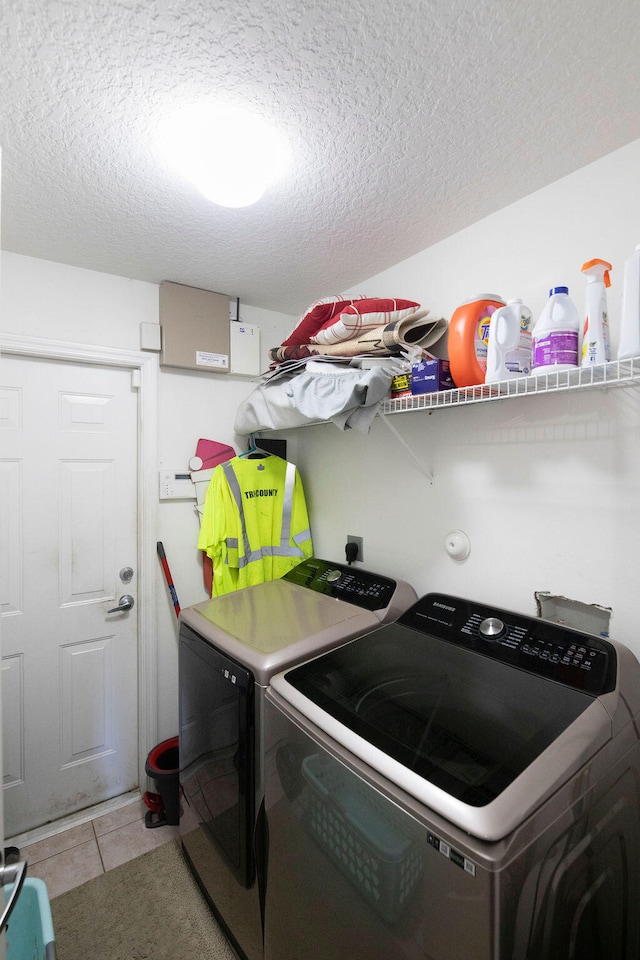 laundry room featuring washing machine and dryer, light tile patterned floors, and a textured ceiling