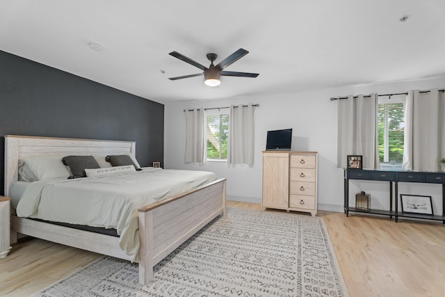 bedroom featuring ceiling fan, light hardwood / wood-style flooring, and multiple windows