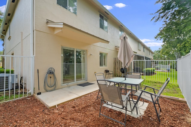 back of house with central AC, a patio area, and a lawn