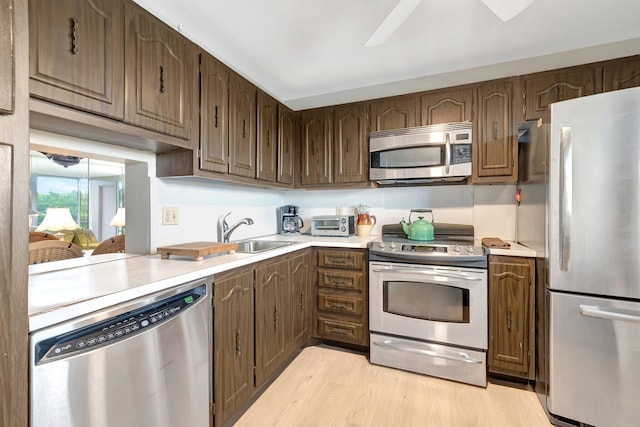 2300 NE 1st Ln Unit 307, Boynton Beach, FL 33435 - kitchen with appliances with stainless steel finishes, a sink, light countertops, light wood finished floors, and ceiling fan