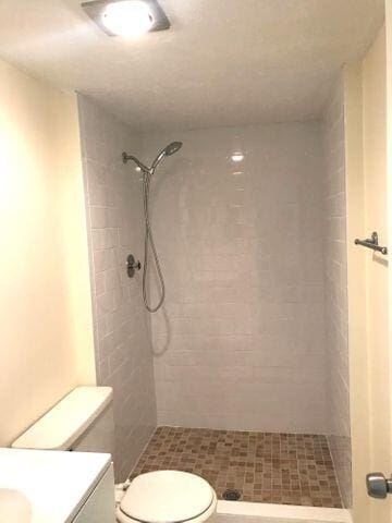 bathroom featuring tiled shower, vanity, and toilet