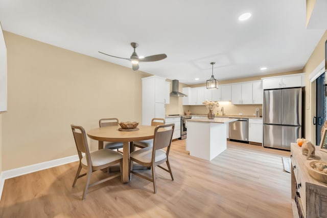 dining room featuring ceiling fan, sink, and light hardwood / wood-style floors