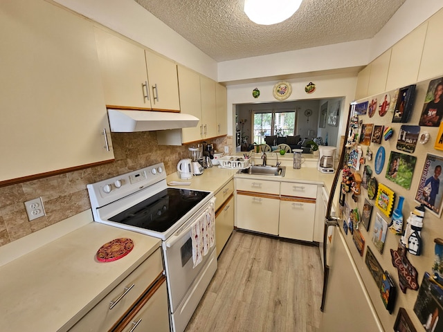 kitchen featuring white appliances, sink, light wood-type flooring, a textured ceiling, and tasteful backsplash