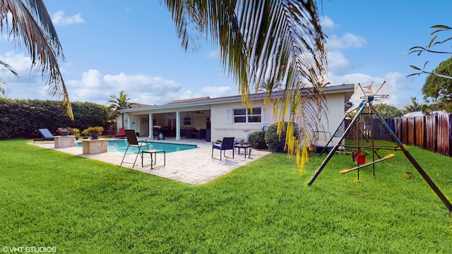 rear view of house with a fenced in pool, ceiling fan, a patio area, and a lawn