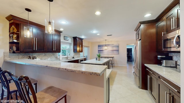 kitchen with pendant lighting, kitchen peninsula, stainless steel appliances, and tasteful backsplash