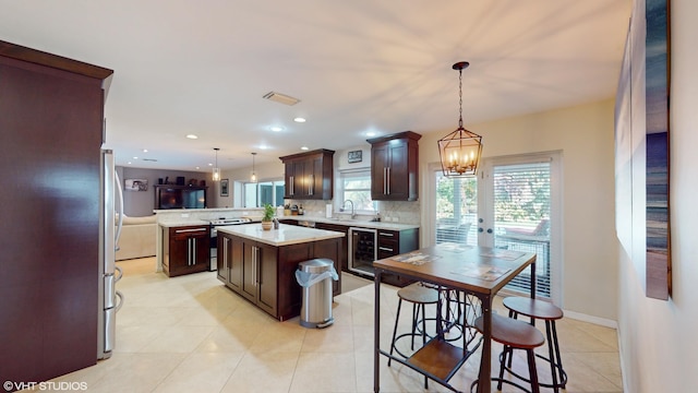 kitchen with kitchen peninsula, wine cooler, decorative light fixtures, and a kitchen island