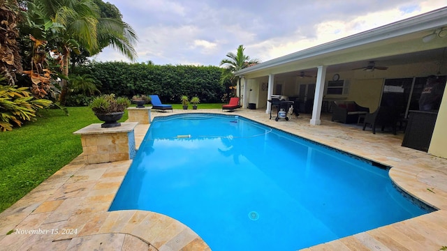 view of swimming pool featuring a lawn, ceiling fan, and a patio