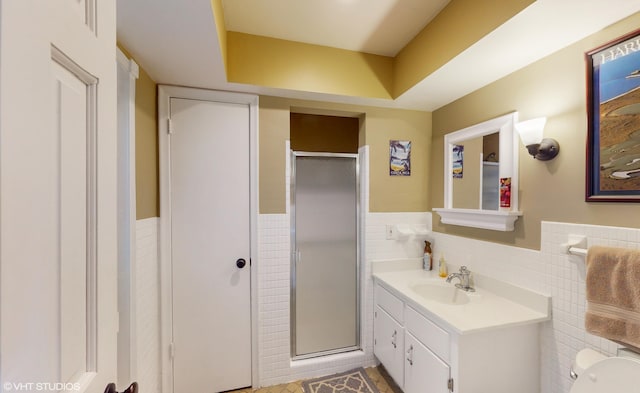 bathroom with vanity, a shower with door, toilet, and tile walls