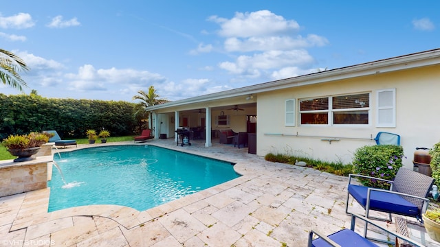 view of swimming pool featuring pool water feature, ceiling fan, a grill, and a patio