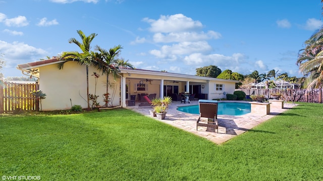 rear view of property featuring a yard, a fenced in pool, a patio, and ceiling fan