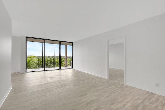 spare room with expansive windows and light hardwood / wood-style floors