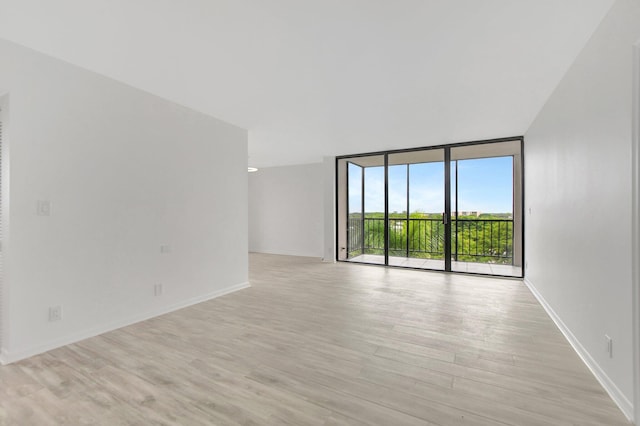 unfurnished room featuring light hardwood / wood-style flooring and a wall of windows