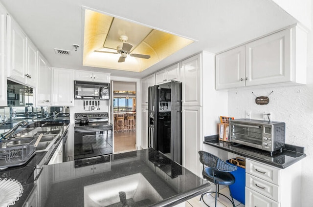 kitchen featuring kitchen peninsula, white cabinets, and black appliances