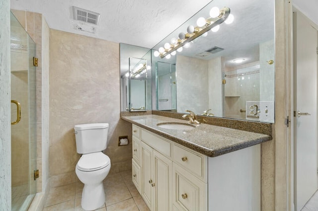 bathroom featuring tile patterned flooring, a textured ceiling, toilet, vanity, and a shower with shower door