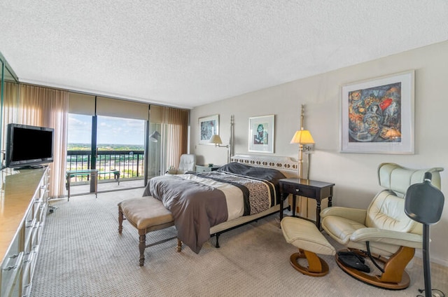 carpeted bedroom featuring access to exterior, a wall of windows, and a textured ceiling