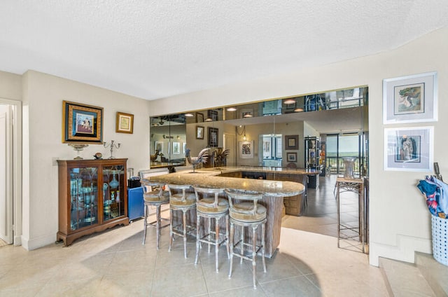 kitchen featuring a kitchen breakfast bar, light tile patterned floors, and a textured ceiling