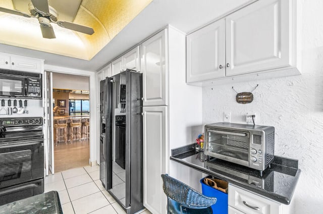 kitchen with black appliances, ceiling fan, light tile patterned flooring, and white cabinetry