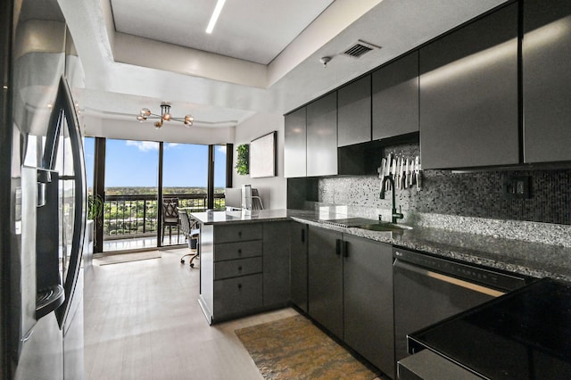 kitchen with sink, backsplash, kitchen peninsula, a tray ceiling, and appliances with stainless steel finishes