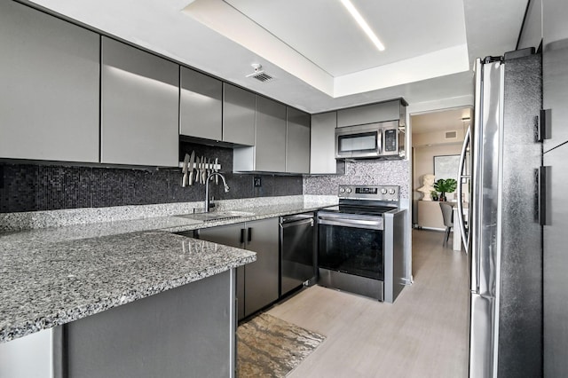 kitchen featuring appliances with stainless steel finishes, light hardwood / wood-style floors, sink, stone counters, and gray cabinets