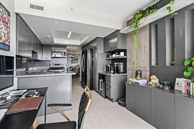 kitchen featuring backsplash, dark stone counters, stainless steel appliances, sink, and light hardwood / wood-style floors