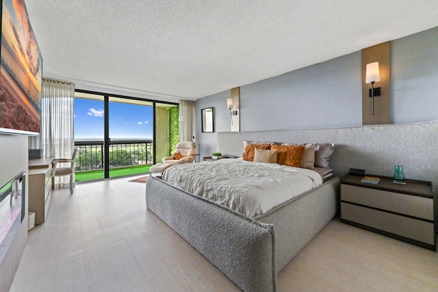 bedroom with a textured ceiling, access to outside, and floor to ceiling windows