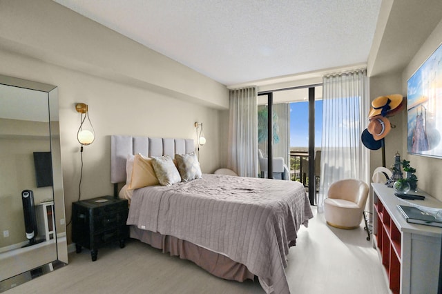 bedroom featuring floor to ceiling windows, access to exterior, and a textured ceiling