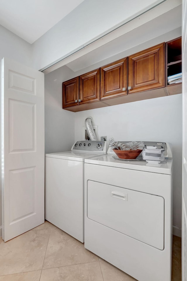 laundry room featuring light tile patterned flooring, cabinets, and independent washer and dryer